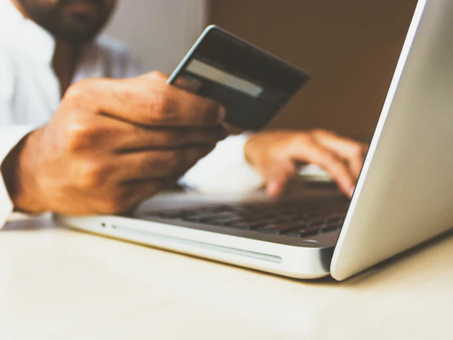 A shopper paying online with a card on a laptop