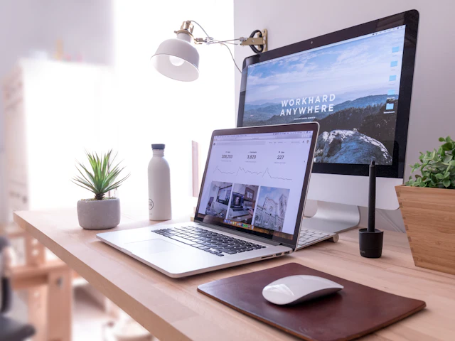 A laptop and desktop screen side by side on a clean work desk
